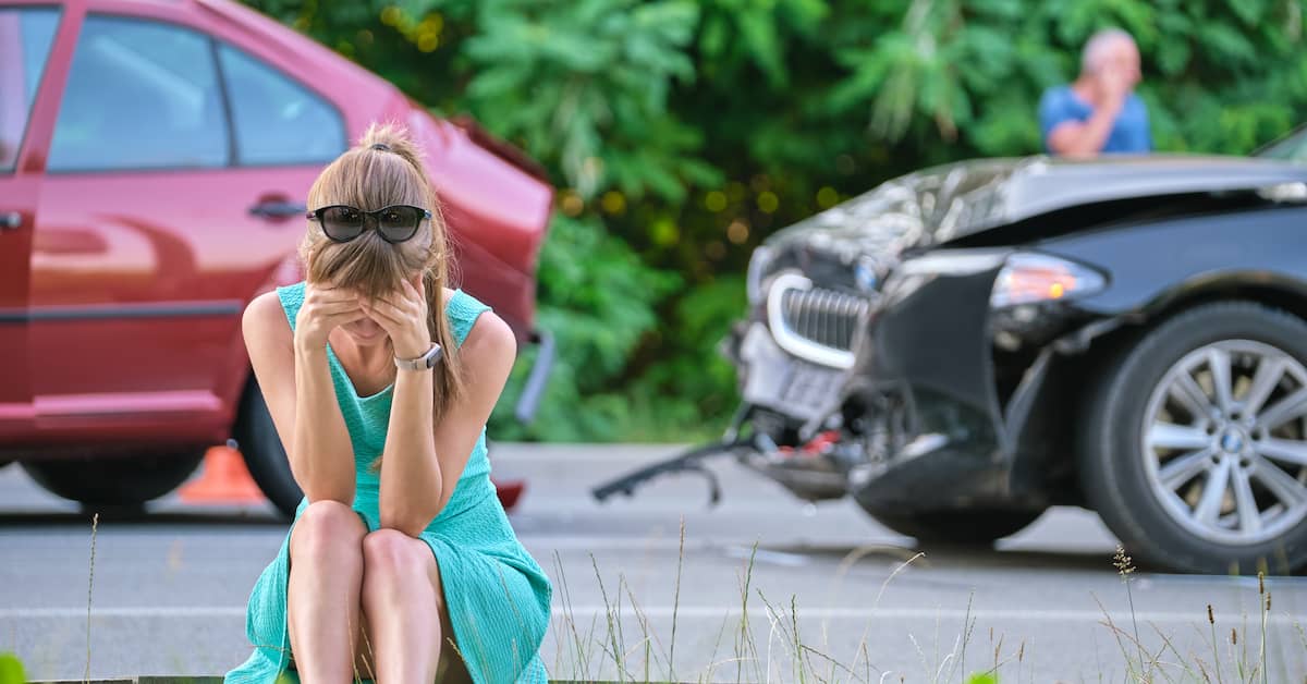 Woman sits on curb after car accident. | Patrick Daniel Law